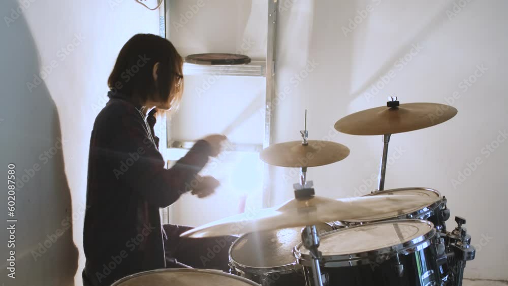 guy playing drums in the light of a lamp