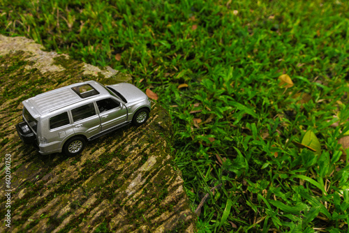 Concept for travelling with a car. Photo of a toy car placed in the park, after some edits.