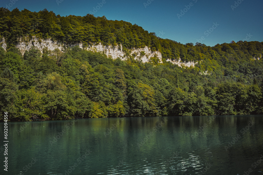 a mountain lake with dark water surrounded by trees with green foliage. summer landscape. a place for rest and relaxation. fresh and clean mountain air. travel around the world