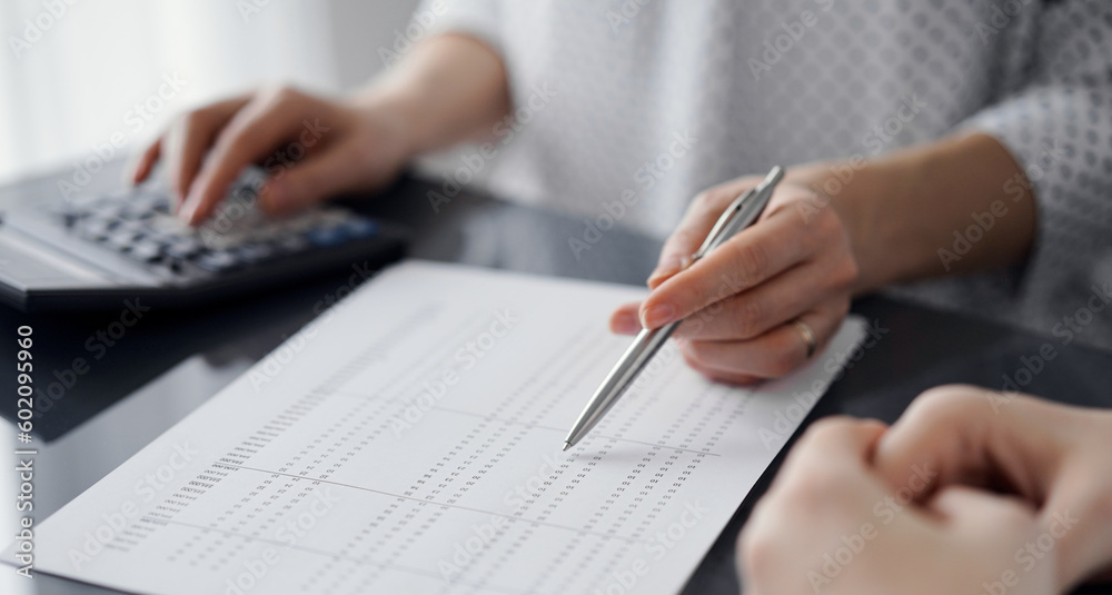 Woman accountant using a calculator and laptop computer while counting taxes for a client. Business audit concepts Woman accountant using a calculator and laptop computer while counting taxes for a client. Business audit concepts