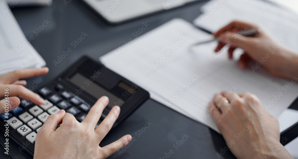 Woman accountant using a calculator and laptop computer while counting taxes for a client. Business audit concepts Woman accountant using a calculator and laptop computer while counting taxes for a client. Business audit concepts