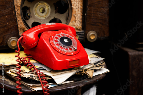 Old red, antique phone between old radios and papers