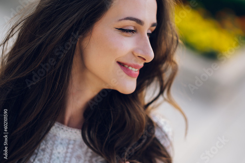 Profile of a happy young woman posing outdoors and smiling.