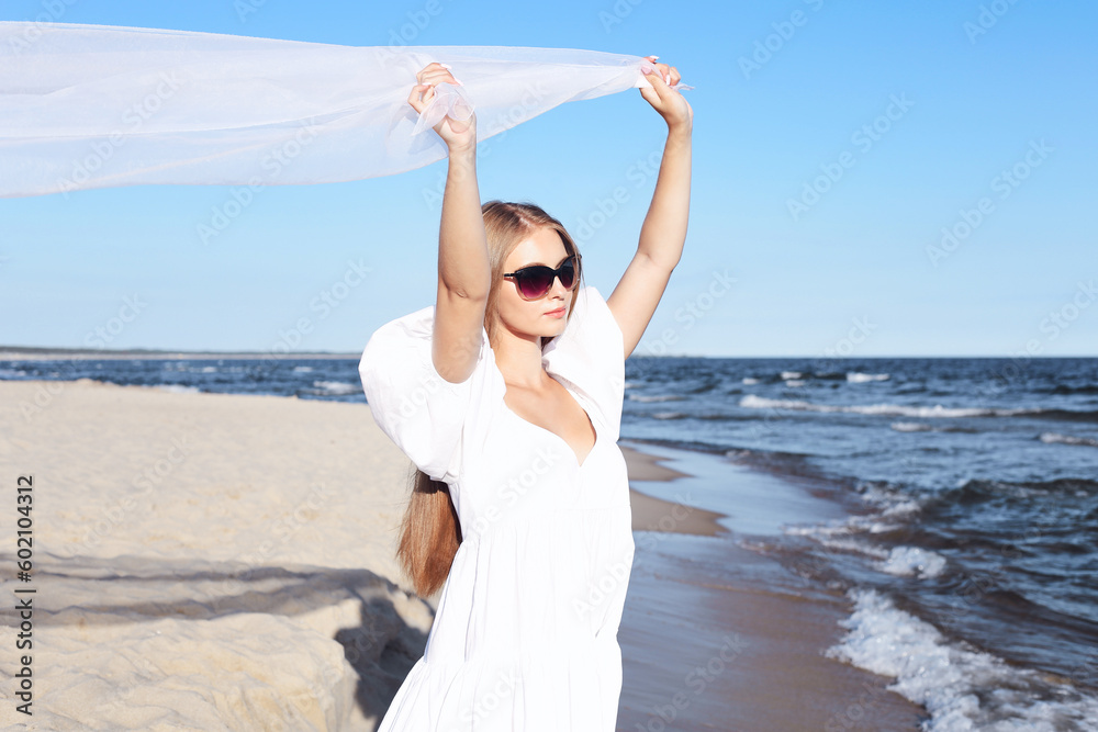 Happy smiling beautiful woman is on the ocean beach in a white summer dress, open arms Happy smiling beautiful woman is on the ocean beach in a white summer dress, open arms