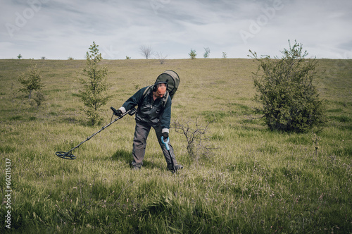 Archaeologist with a metal detector. Archaeologist man looking for burial concept. An employee of the archaeological expedition holds a metal detector. Guy with a shovel digs a treasure