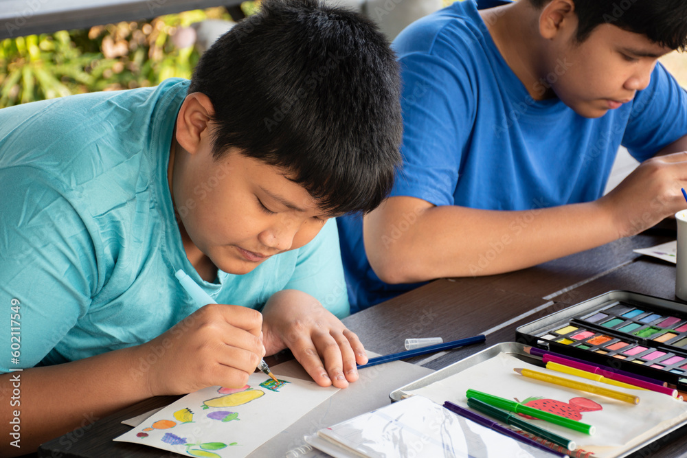 Asian boys are spending their free times with drawing, sketching, coloring and painting by using watercolor bars in cases, teenagers activity in summer and watercolor lesson concept. Asian boys are spending their free times with drawing, sketching, coloring and painting by using watercolor bars in cases, teenagers activity in summer and watercolor lesson concept.