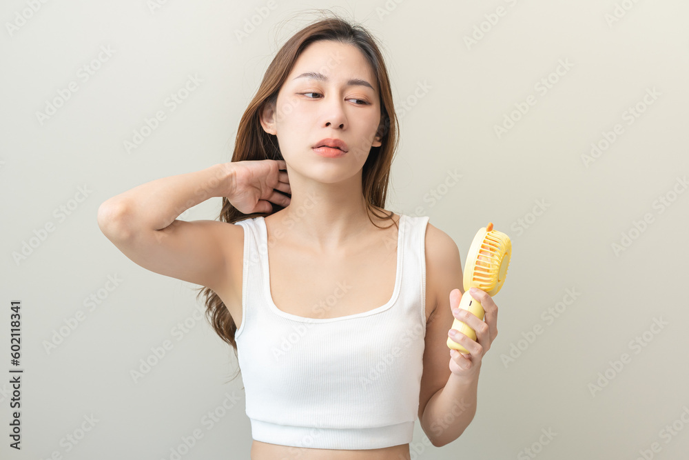 Suffering summer heat wave stroke, hot weather, tired asian young woman sweaty, refreshing with using portable fan hand, blowing wave fan to ventilation when temperature high, isolated on background. Suffering summer heat wave stroke, hot weather, tired asian young woman sweaty, refreshing with using portable fan hand, blowing wave fan to ventilation when temperature high, isolated on background.