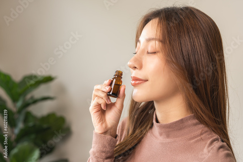 Aromatherapy, attractive asian young woman, girl face expression enjoying smell fragrance of herbal from medicine natural organic essential perfume oil at home. Therapy treatment, beauty skin care.
