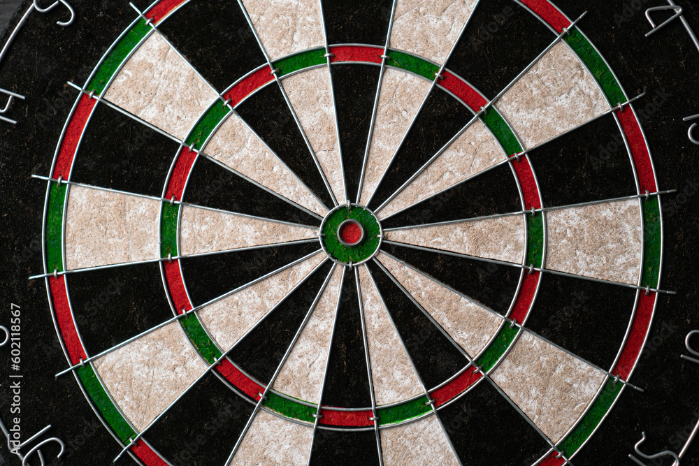 New classic professional sisal dart board on black wooden background. Close up. New classic professional sisal dart board on black wooden background. Close up.