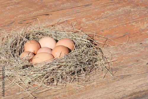 Brown eggs in a light wooden basket, nest. Farm food product. Beautiful sunny background with eggs.