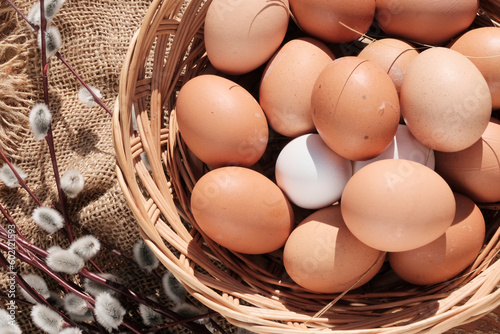 Beautiful brown colored eggs in a wooden basket in sunlight. Farmer's market, Egg price, increase. dietary product. Beautiful background with eggs.
