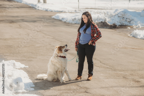 Woman giving sit command to large white dog in winter