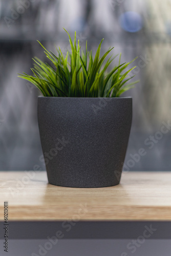 Green artificial grass with a lot of plastic stems in gray concrete flower pot