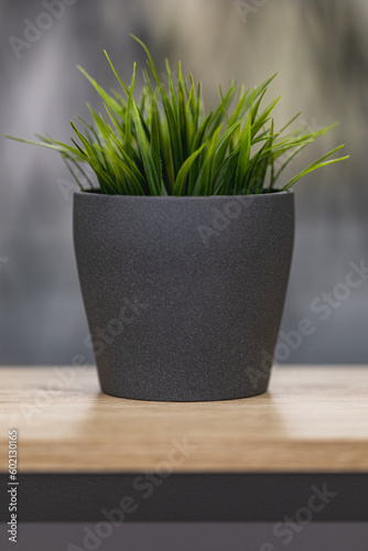 Green artificial grass with a lot of plastic stems in gray concrete flower pot