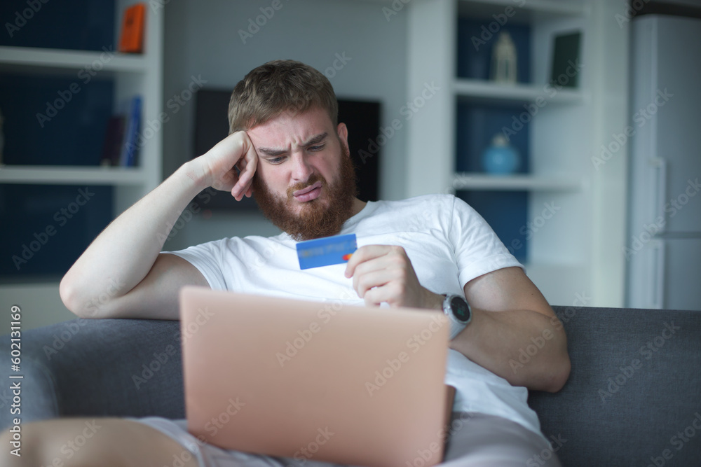 Nervous sad upset confused young man, stressed worried guy having problem with paying, buying online, payments with credit blocked bank card, looking at screen, monitor of laptop. Internet fraud Nervous sad upset confused young man, stressed worried guy having problem with paying, buying online, payments with credit blocked bank card, looking at screen, monitor of laptop. Internet fraud