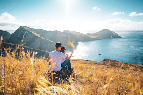 Back view of a young tourist couple enjoying the view on coastal landscape of Madeira Island in the Atlantic Ocean in the morning. São Lourenço, Madeira Island, Portugal, Europe.