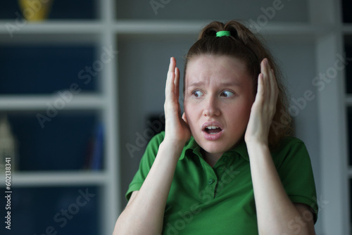 Fototapeta Young european woman sitting on the sofa at home afraid and shocked with surprise expression, fear and excited face