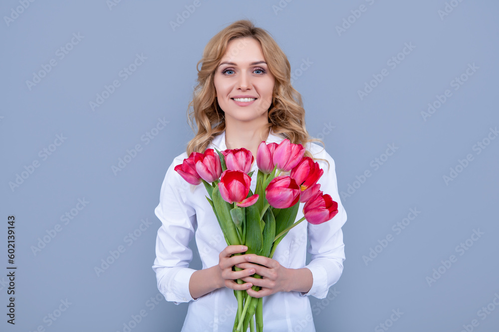 happy blond woman with spring tulip flowers on grey background