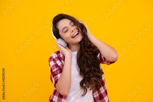 Young teen child listening music with headphones. Girl listening songs via wireless headphones. Wireless headset device accessory.