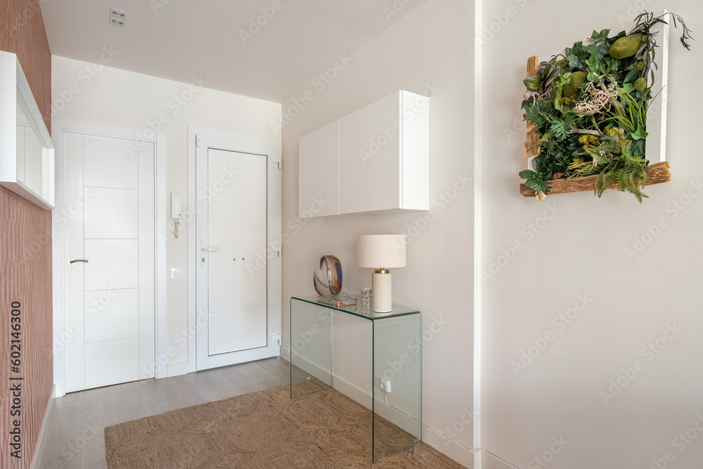 Simple but cozy entrance hall in light colors with an intercom, a glass console and a hanging cabinet with a stylish herbarium on the wall. The concept of simple concise interior design Simple but cozy entrance hall in light colors with an intercom, a glass console and a hanging cabinet with a stylish herbarium on the wall. The concept of simple concise interior design