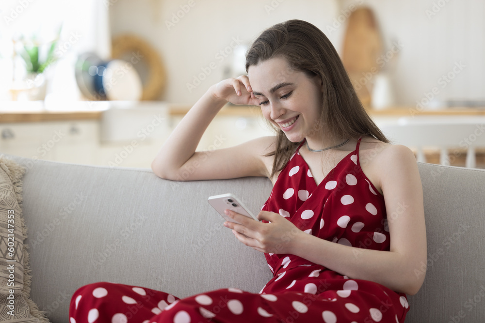Happy beautiful young woman using smartphone for online shopping on Internet fashion stores, holding cellphone, resting on home sofa, smiling, laughing, enjoying Internet communication technology Happy beautiful young woman using smartphone for online shopping on Internet fashion stores, holding cellphone, resting on home sofa, smiling, laughing, enjoying Internet communication technology