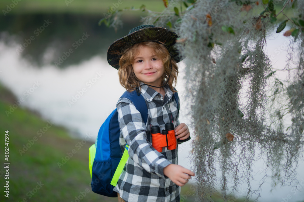 Little child with backpack and binoculars. Imagination or exploration in park. Happy child playing with binocular. Young tourist explorer. Child vacation and travel. Summer journey for kids. Little child with backpack and binoculars. Imagination or exploration in park. Happy child playing with binocular. Young tourist explorer. Child vacation and travel. Summer journey for kids.
