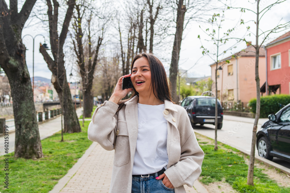 A young girl is talking on a phone waiting for a friend in the city during the day A young girl is talking on a phone waiting for a friend in the city during the day