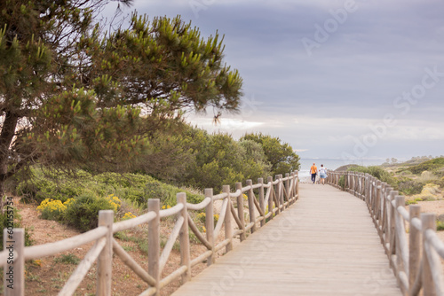 People walking on wooden walkway along the beach.