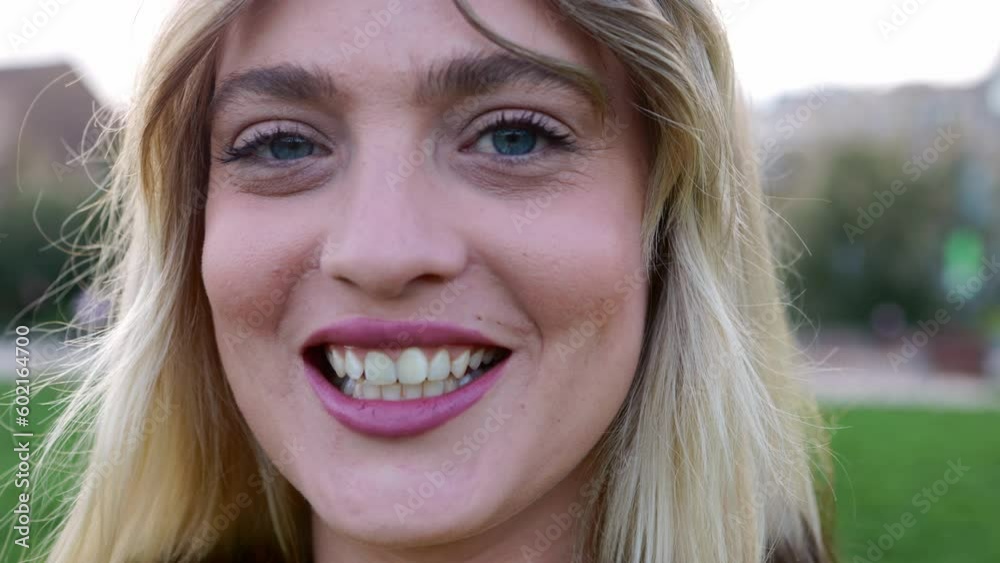 Close up portrait of young trendy blonde woman smiling at camera outdoors. Beauty blonde girl standing at city park. Close up portrait of young trendy blonde woman smiling at camera outdoors. Beauty blonde girl standing at city park.