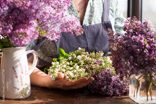 A floristic woman collects a bouquet of lilac flowers. Flower shop