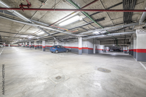 A few parking spaces of a large garage in an urban residential apartment building with white