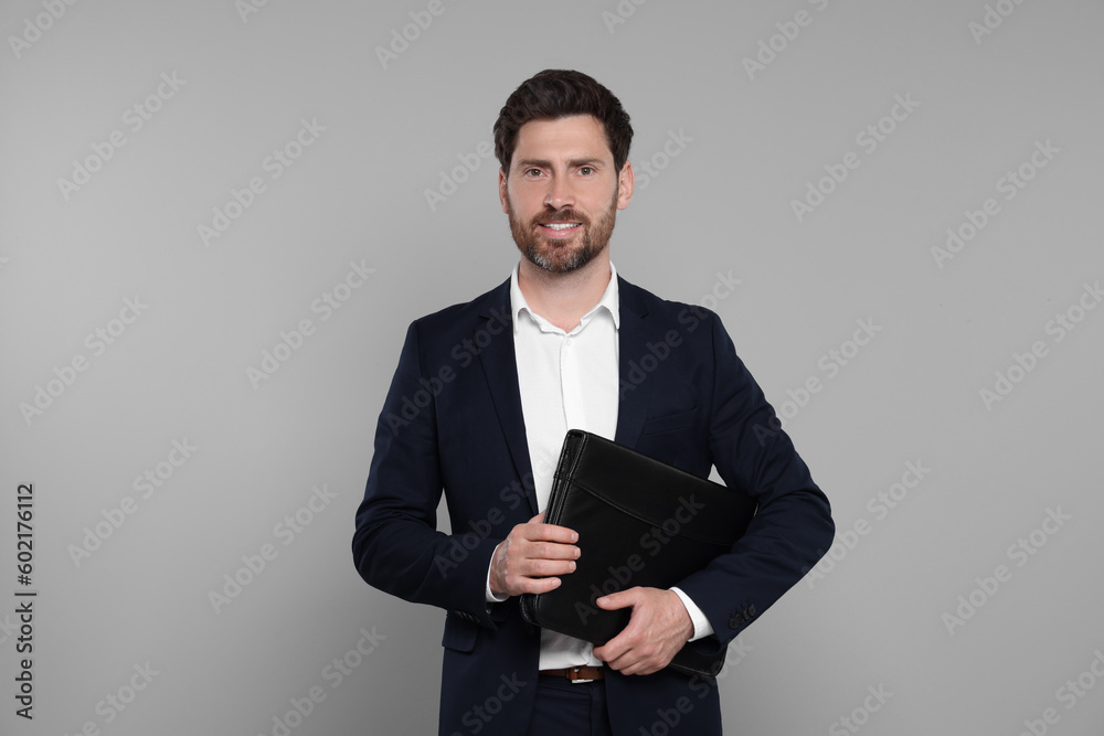 Happy real estate agent with leather portfolio on grey background Happy real estate agent with leather portfolio on grey background