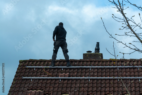 Installing of solar panels on roof in cloudy winter day, green energy in Europe