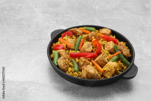 Serving pan of delicious rice with chicken and vegetables on light grey table