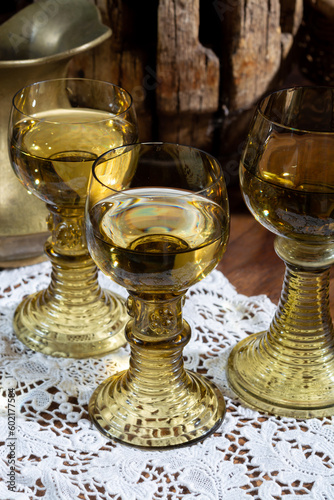 Antique German glassware, old Dutch style rummer or roemer glasses with white wine on white lace tablecloth photo