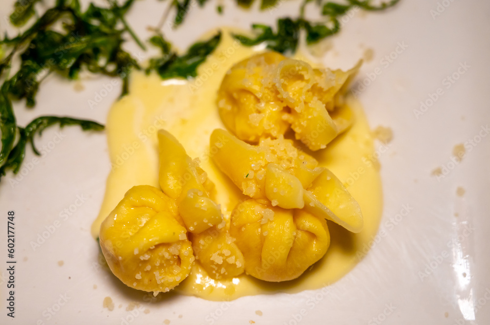 Italian food, fresh home made pumpkin stuffed pasta tortellini or ravioli dumplings with parmesan parmigiano reggiano cheese sauce with dried rocket salad Italian food, fresh home made pumpkin stuffed pasta tortellini or ravioli dumplings with parmesan parmigiano reggiano cheese sauce with dried rocket salad