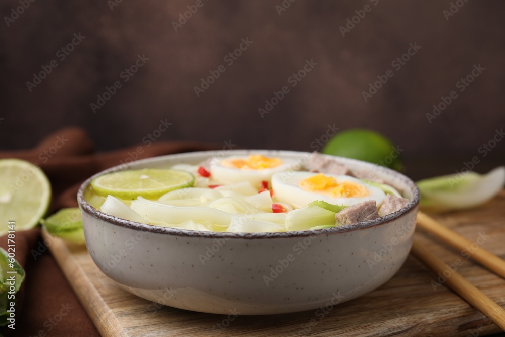 Bowl of delicious rice noodle soup with meat and egg on wooden board, closeup Bowl of delicious rice noodle soup with meat and egg on wooden board, closeup