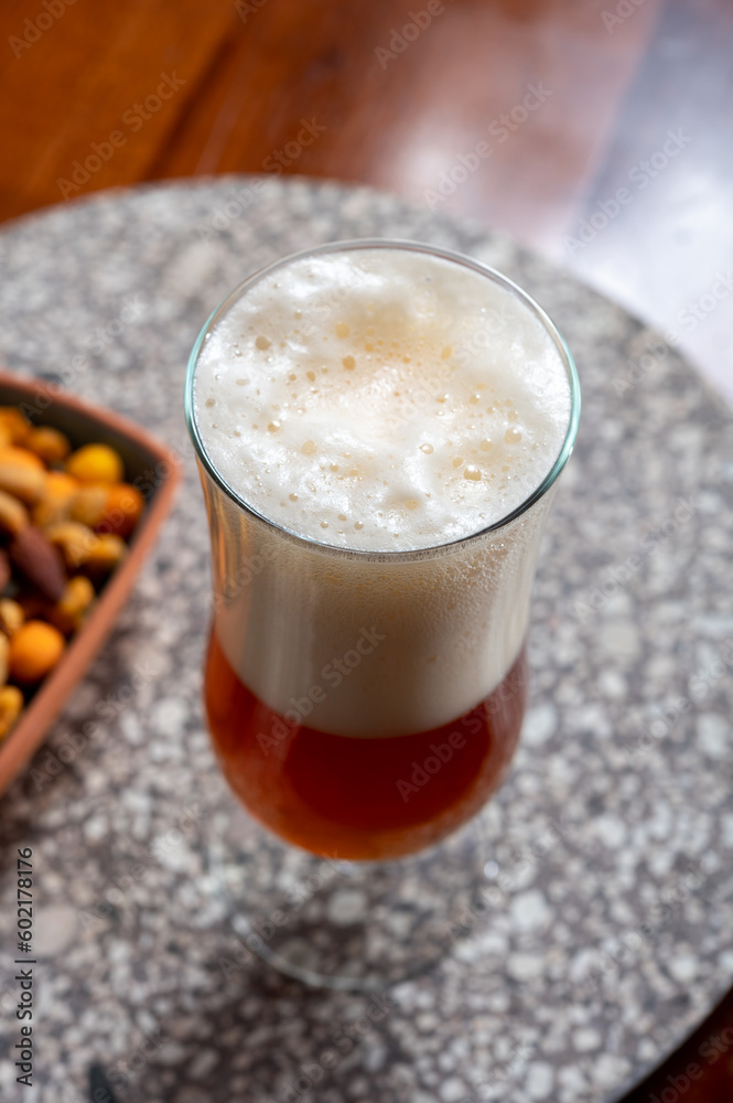 Glass of Belgian light blond beer made in abbey and bowl with party mix nuts Glass of Belgian light blond beer made in abbey and bowl with party mix nuts
