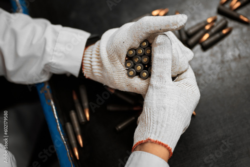 Employee in gloves holds riffle cartridges at workplace