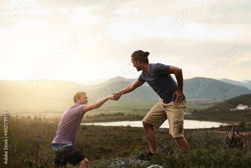 Hiker helping friend while hiking, fitness and men outdoor trekking in nature or countryside for exercise and travel. Young people hike together, support and adventure with friends, bond and workout