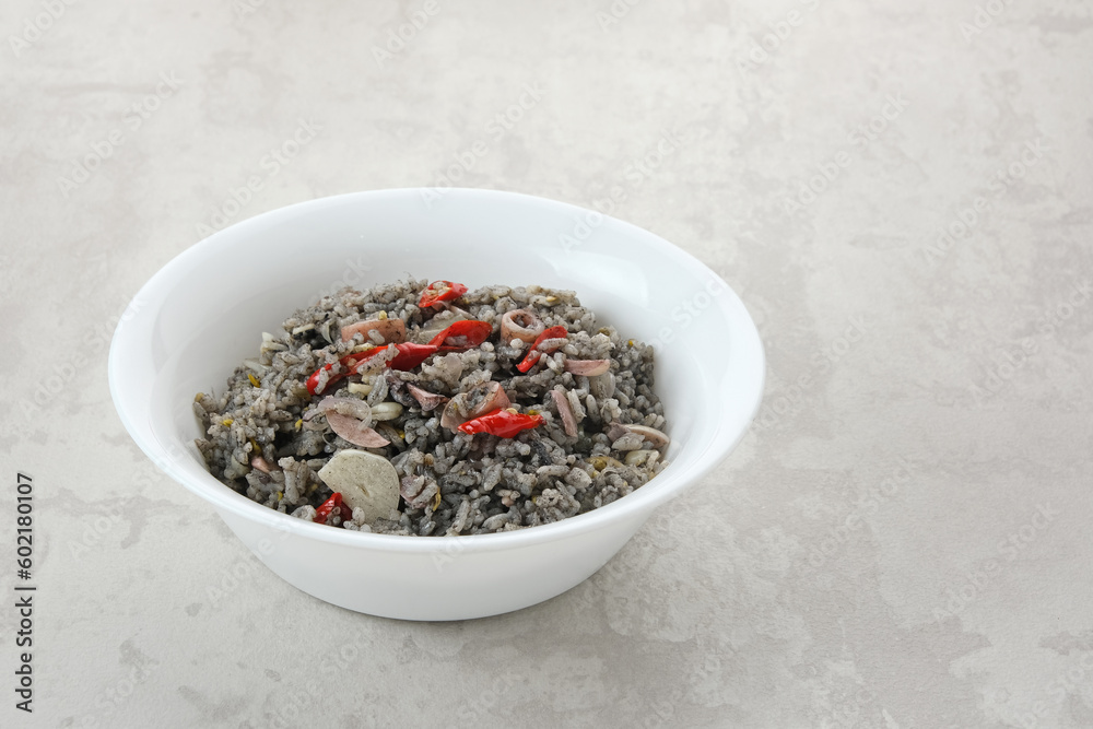Nasi Goreng Cumi Hitam or Black Squid Fried Rice, served in white plate on wooden table
Nasi Goreng Cumi Hitam or Black Squid Fried Rice, served in white plate on wooden table