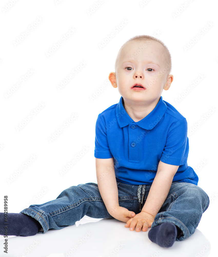 Young boy with Downs syndrom wearing casual clothes sits and looks at camera. Isolated on white background Young boy with Downs syndrom wearing casual clothes sits and looks at camera. Isolated on white background