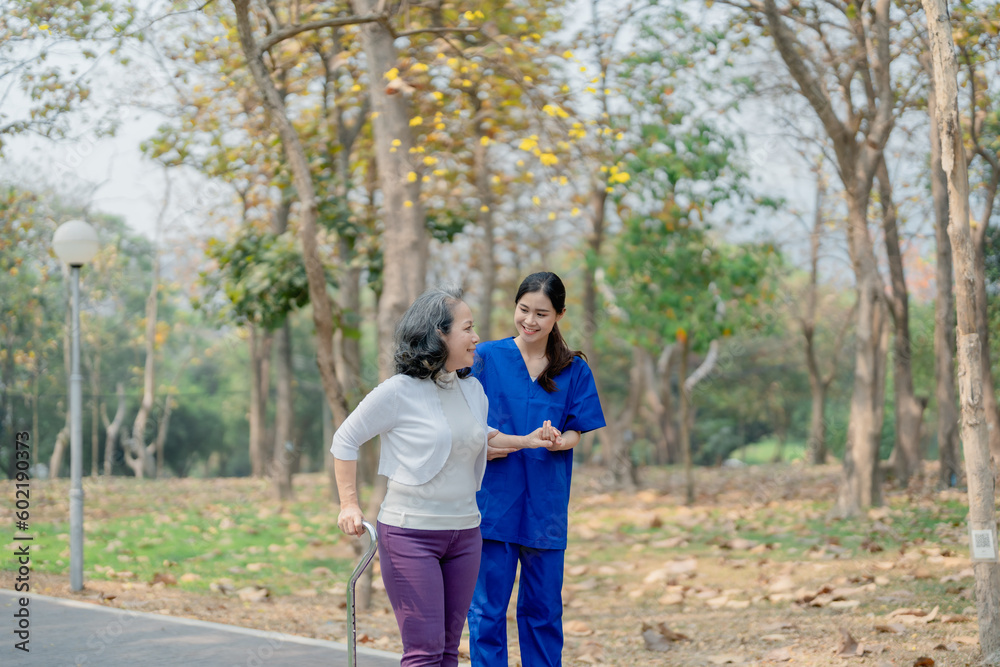 woman physiotherapist is holding a female elderly patient walking in a park to strengthen her leg muscles. woman physiotherapist is holding a female elderly patient walking in a park to strengthen her leg muscles.