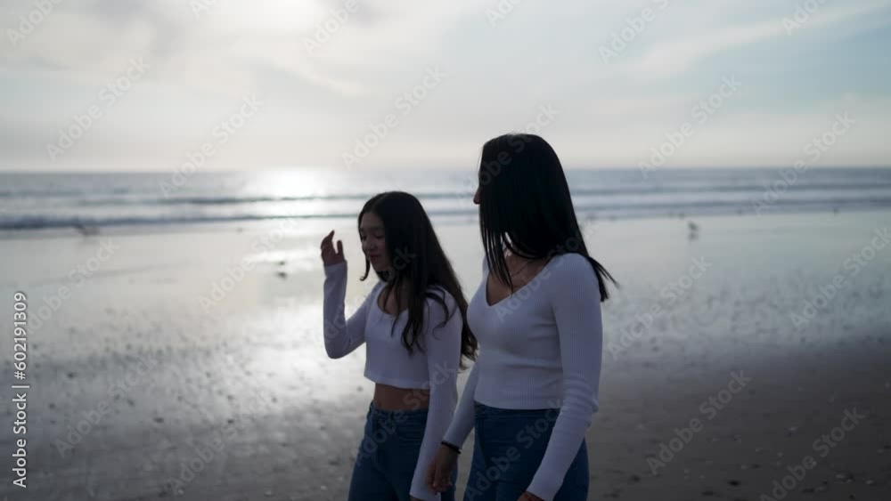 mid adult latin mother and daughter walking on the beach talking relaxed mid adult latin mother and daughter walking on the beach talking relaxed