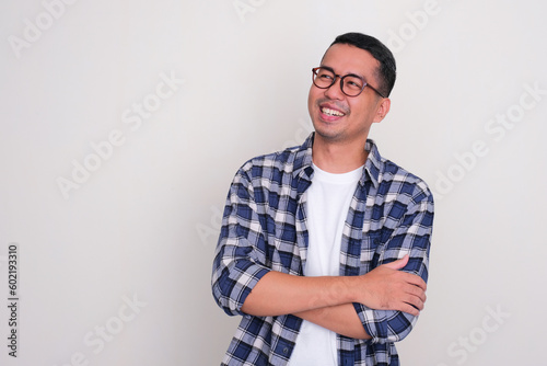 Adult Asian man smiling with arms crossed looking to the right side