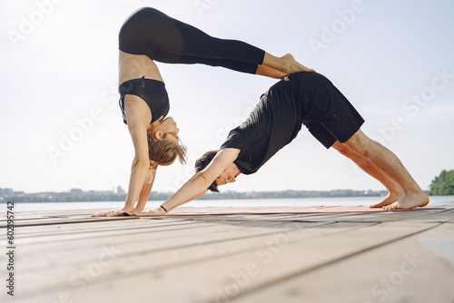 Man and woman doing yoga exercises by the water
