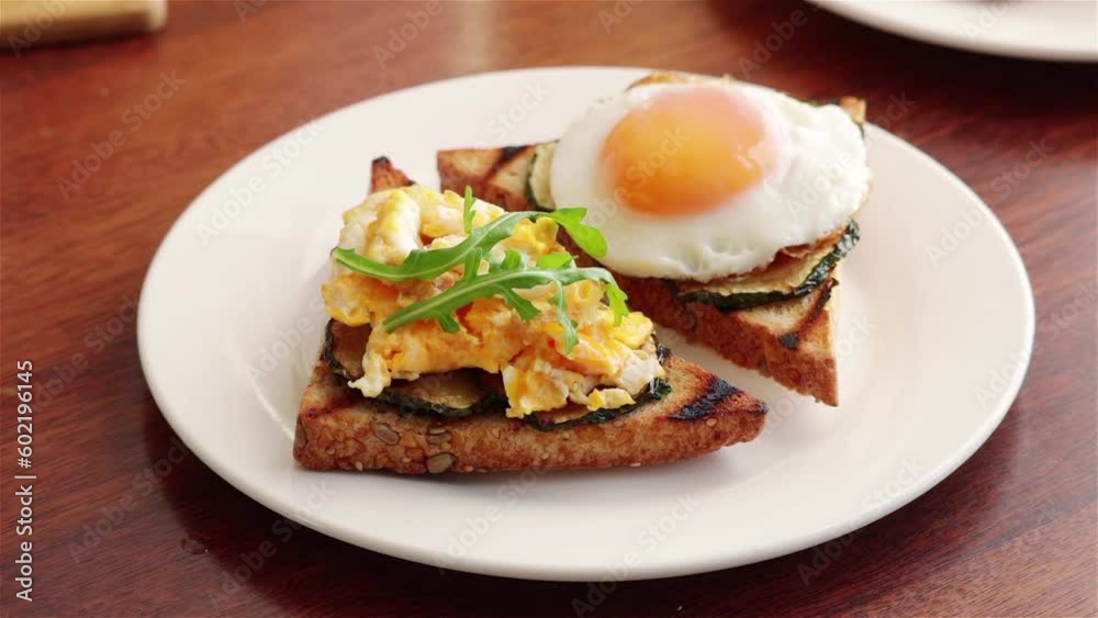 man hand put arugula leaves on healthy sandwich with fried egg grilled zucchini on white plate man hand put arugula leaves on healthy sandwich with fried egg grilled zucchini on white plate
