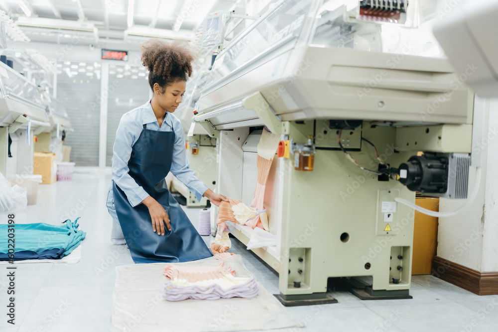 custom made wallpaper toronto digitalAmerican female designer is a seamstress. sitting inspecting the fabric she designed near a sewing machine in a large weaving factory There are many machines working. She's wearing a uniform.