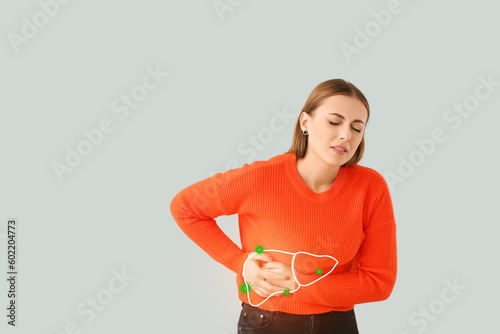 Young woman suffering from pain in liver on light background. Hepatitis problem