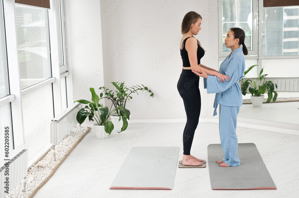 Caucasian woman stands on sadhu boards with therapist support. Caucasian woman stands on sadhu boards with therapist support.